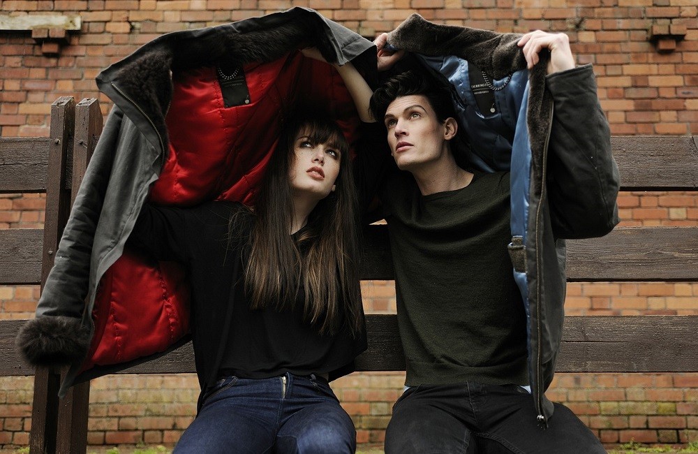 A young couple hold their jackets above their heads to protect themselves from wet weather