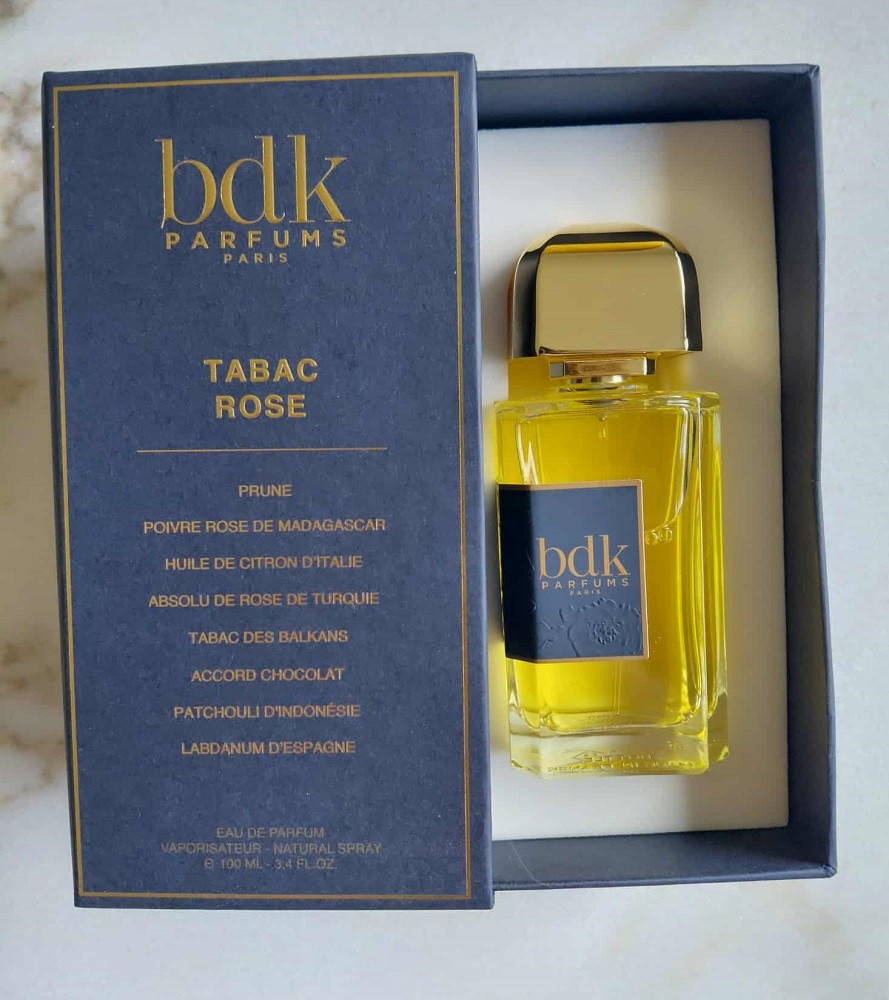 A rectangular bottle of Tabac Rose by BDK Parfums sits nested inside the box it comes in