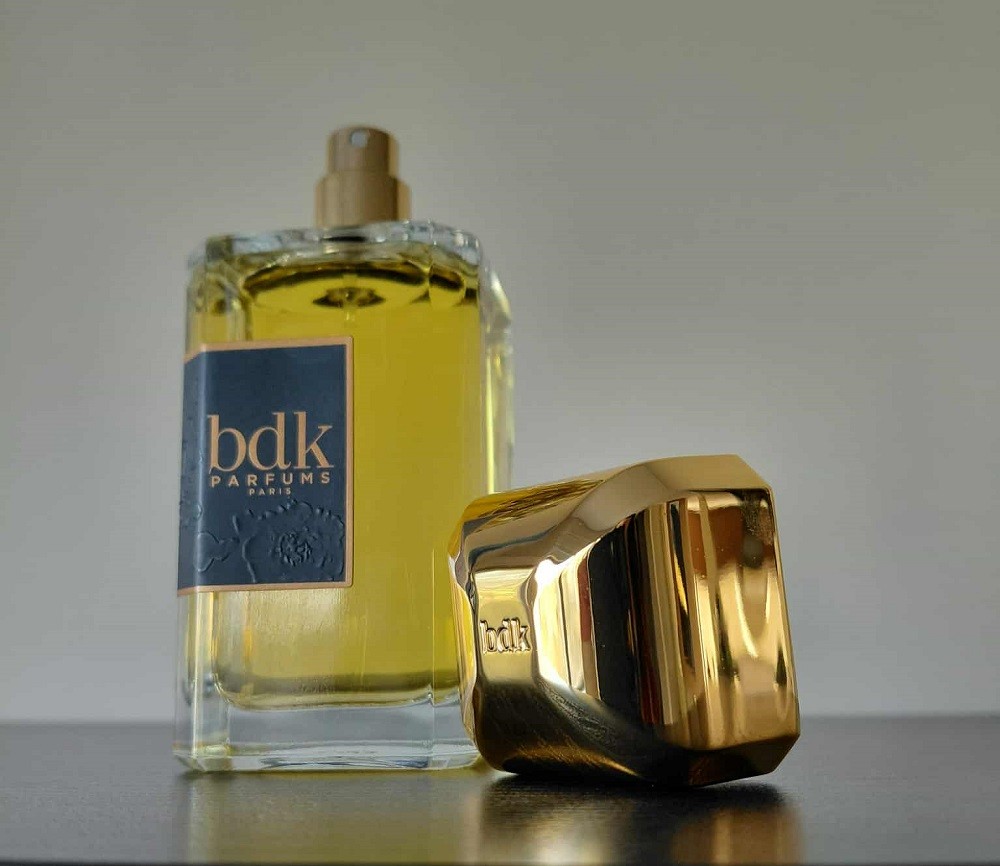 A rectangular bottle of Tabac Rose by BDK has its large gold cap sitting beside it