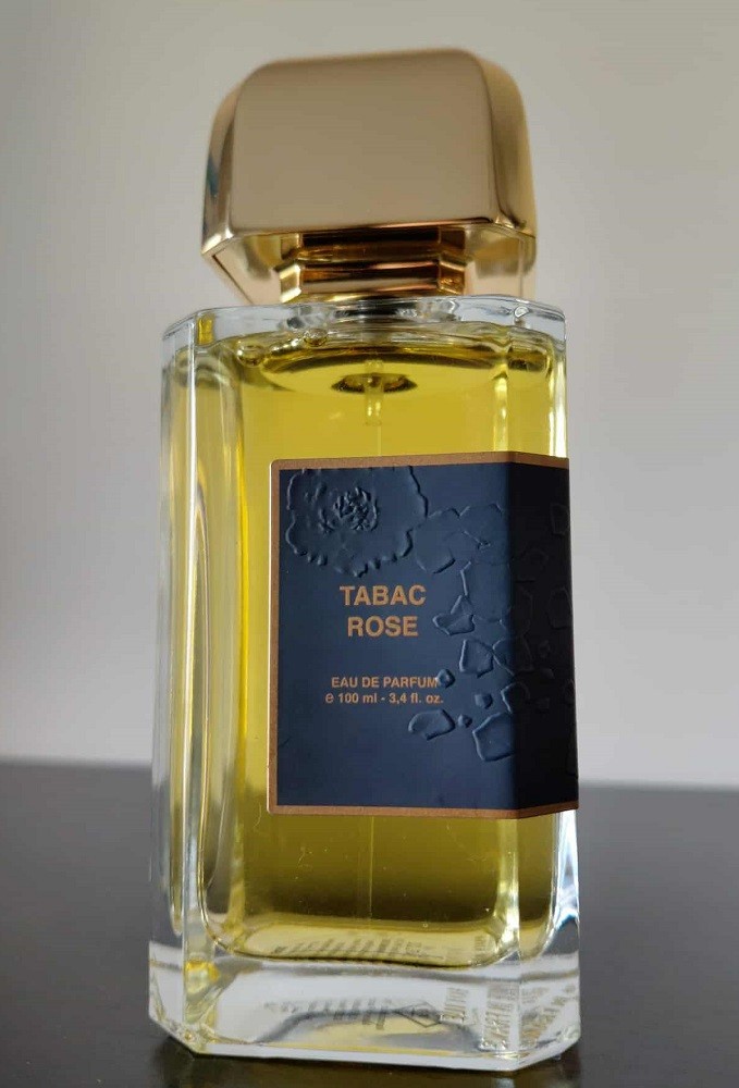 The clear rectangular bottle of Tabac Rose by BDK Parfums has a dark blue label on it