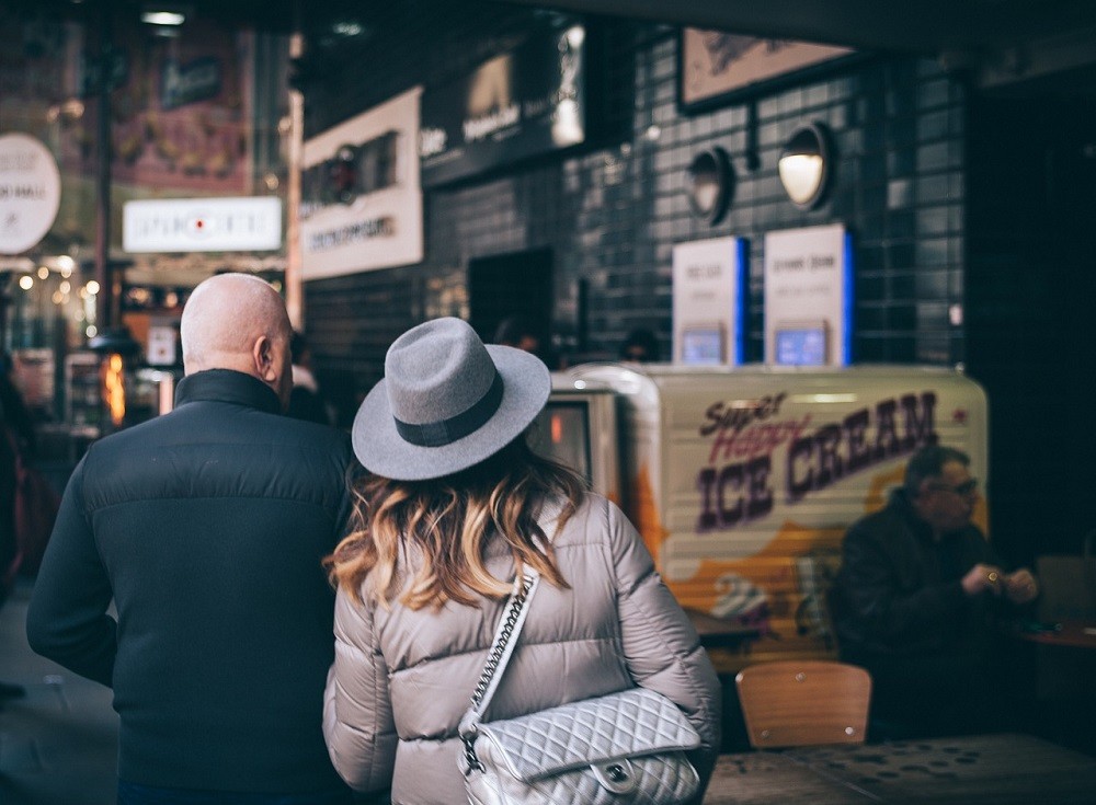 A man and woman are walking through a small cafe looking for a place to sit
