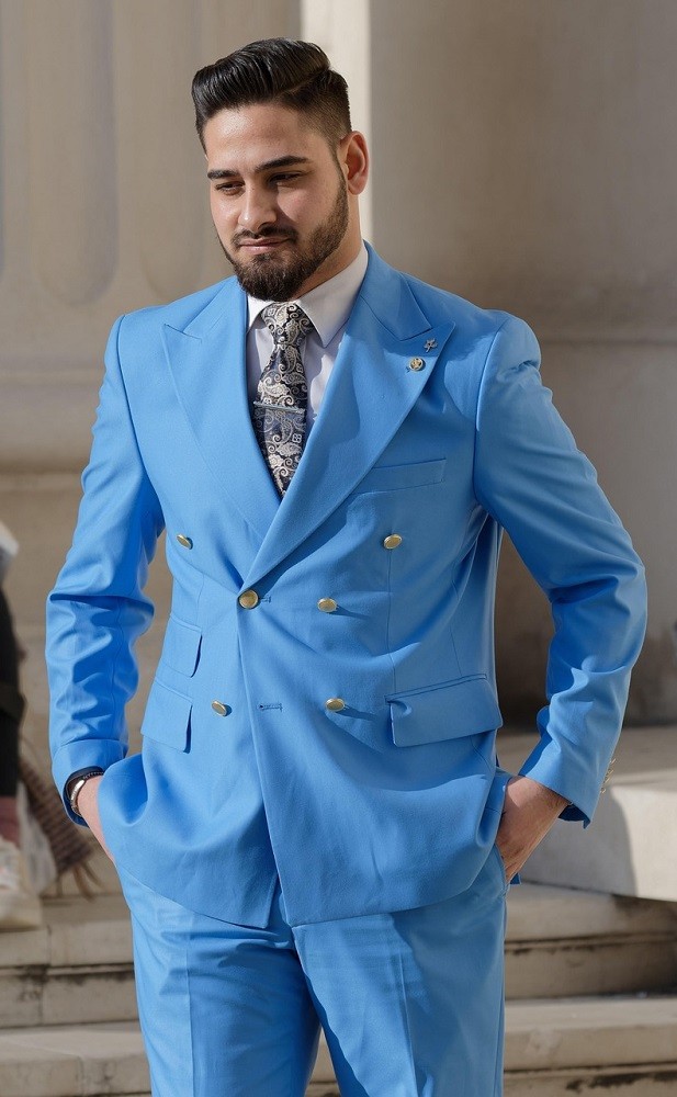 A man in a light blue double breasted suit is walking down stairs
