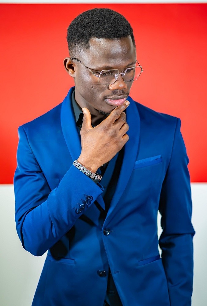 A man wearing a blue suit had his hand to his chin like he is thinking