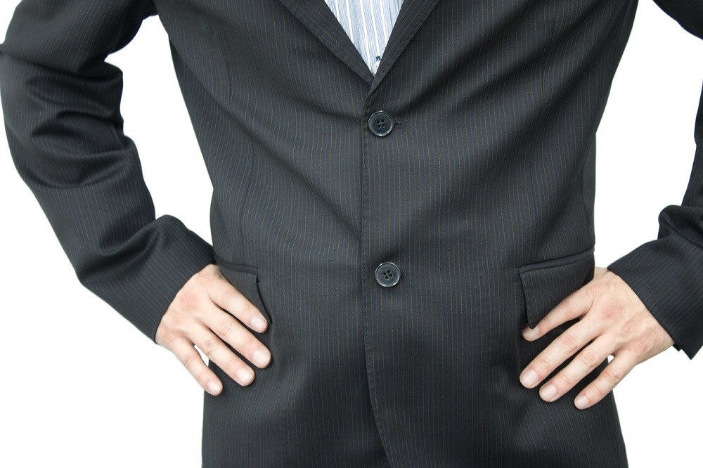A man is wearing a black suit and has both the buttons done up. This is the incorrect way to button a suit