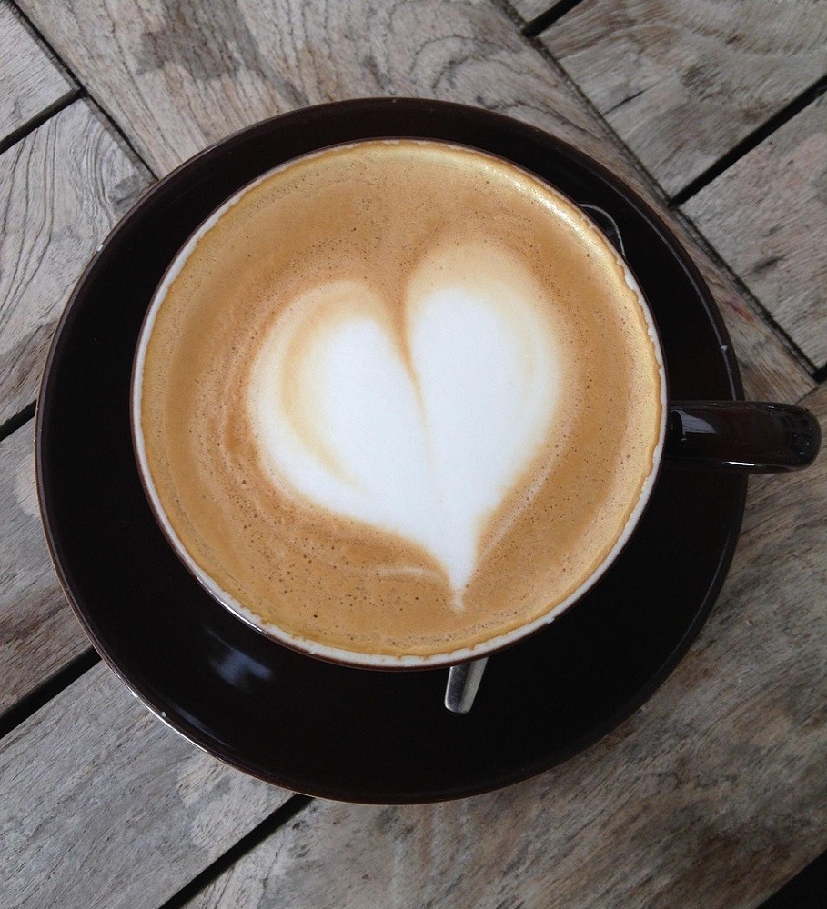 A latte with a heart shaped design inside a black coffee mug