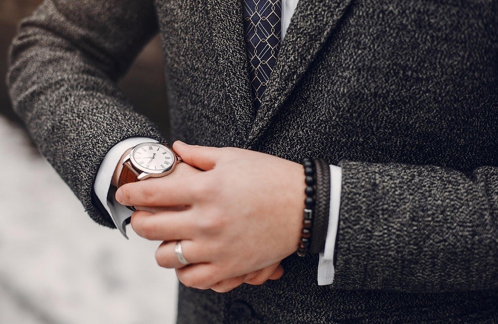 A man is looking at his white dress watch