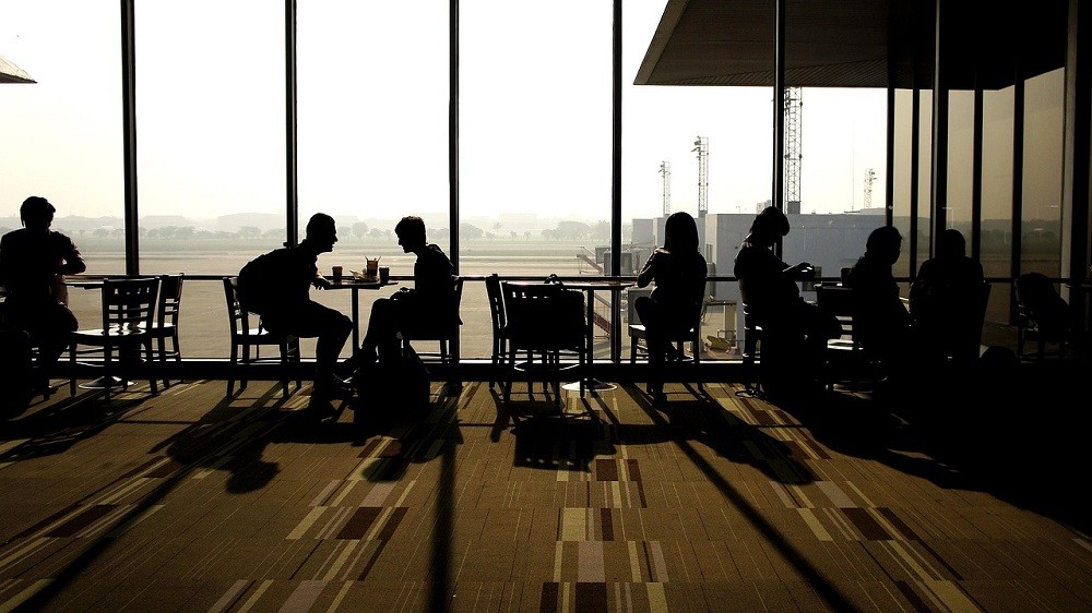 Several tables at a coffee shop show people sitting and conversing