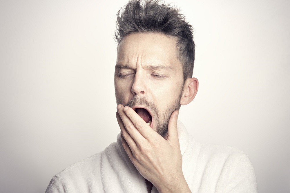 A middle-aged man politely covers his mouth while he yawns