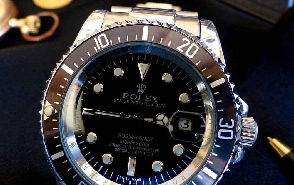 A black dialed Rolex Submariner with a silver case and metal strap sits on a black velvet cloth