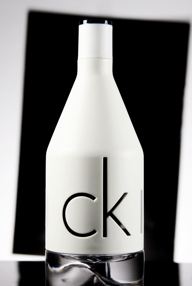A white bottle of Calvin Klein cologne with a clear bottom sits on a black countertop