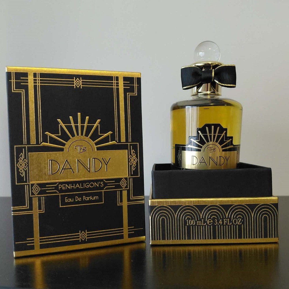 A bottle of The Dandy by Penhaligon's sits nested inside of the black and gold art deco box it comes in