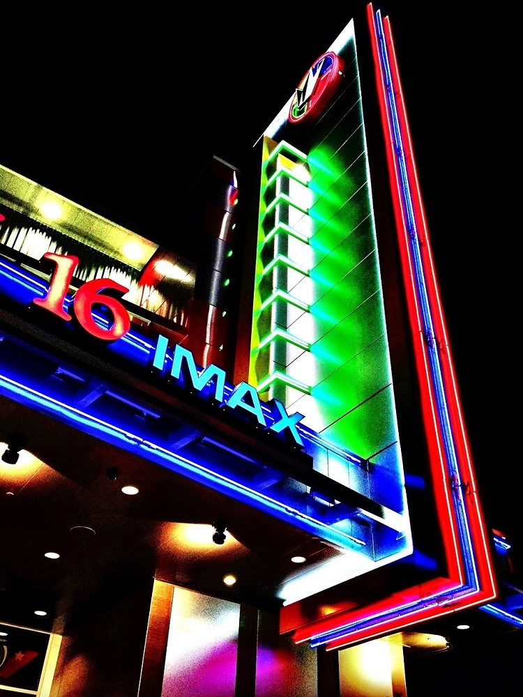 The exterior of a movie theatre with a colourful neon light display