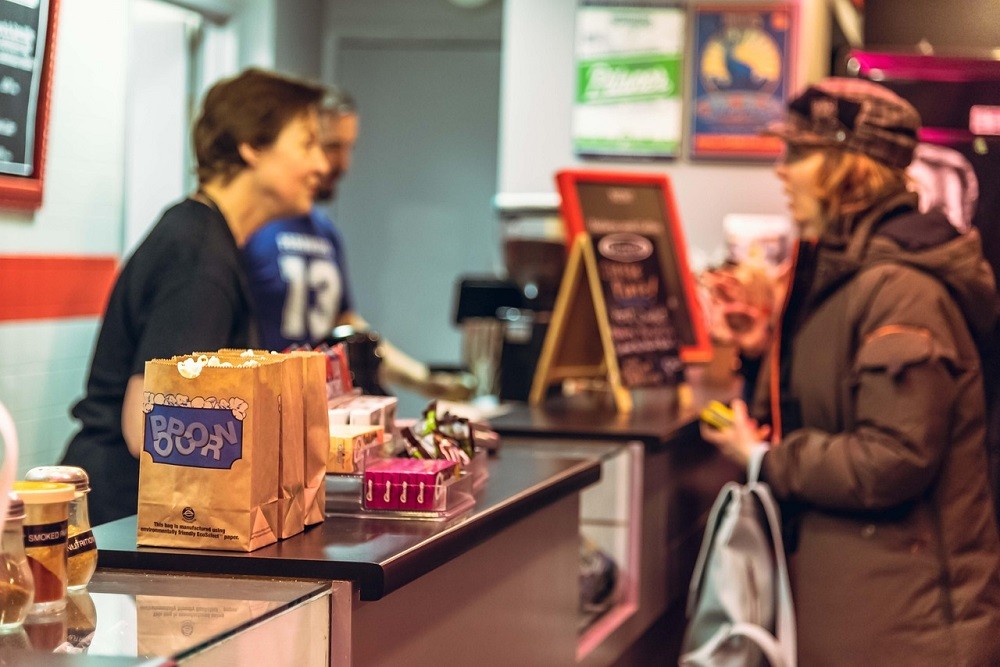 A woman is purchasing snacks from a movie theatre concession
