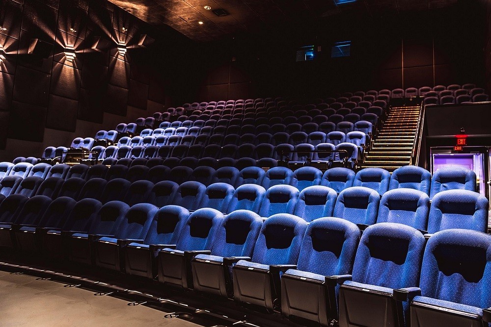 A clean movie theatre with blue seats is ready for the next group of moviegoers