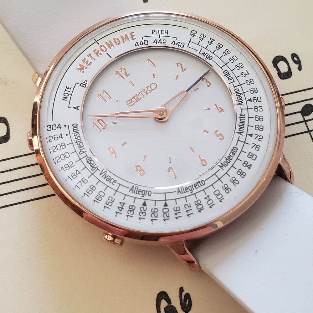 A closeup of the dial of the Seiko Metronome watch shows the various tempos it can be set to, numerals to mark the hours, and gold minute and hour hands