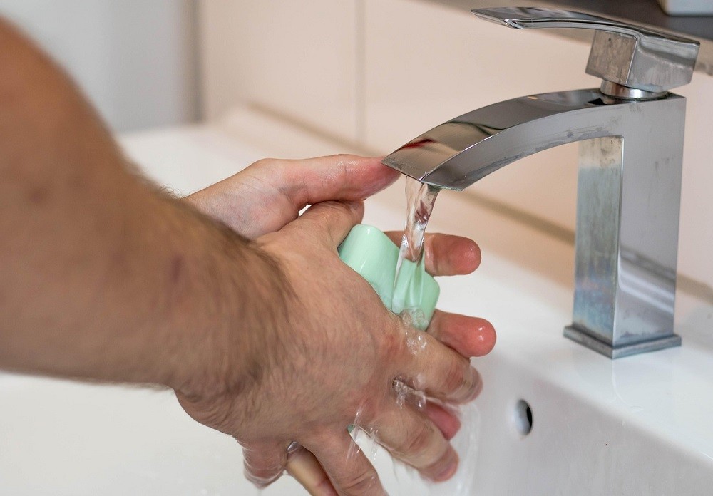 A man is washing his hands with soap and water in a sink