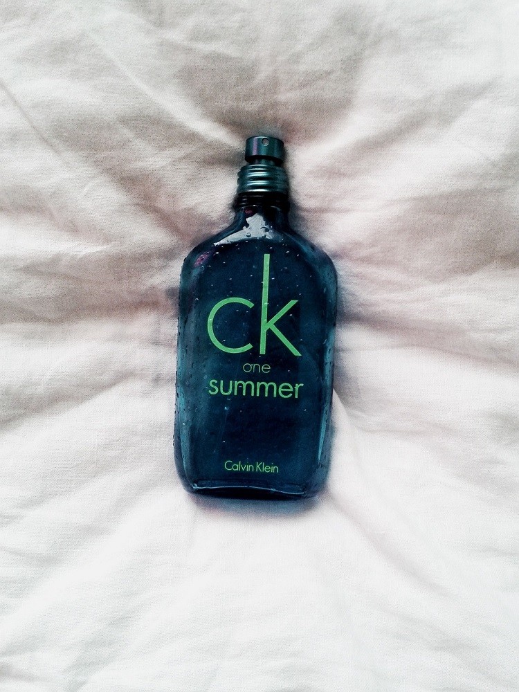 A blue bottle of cologne is covered in condensation from humidity