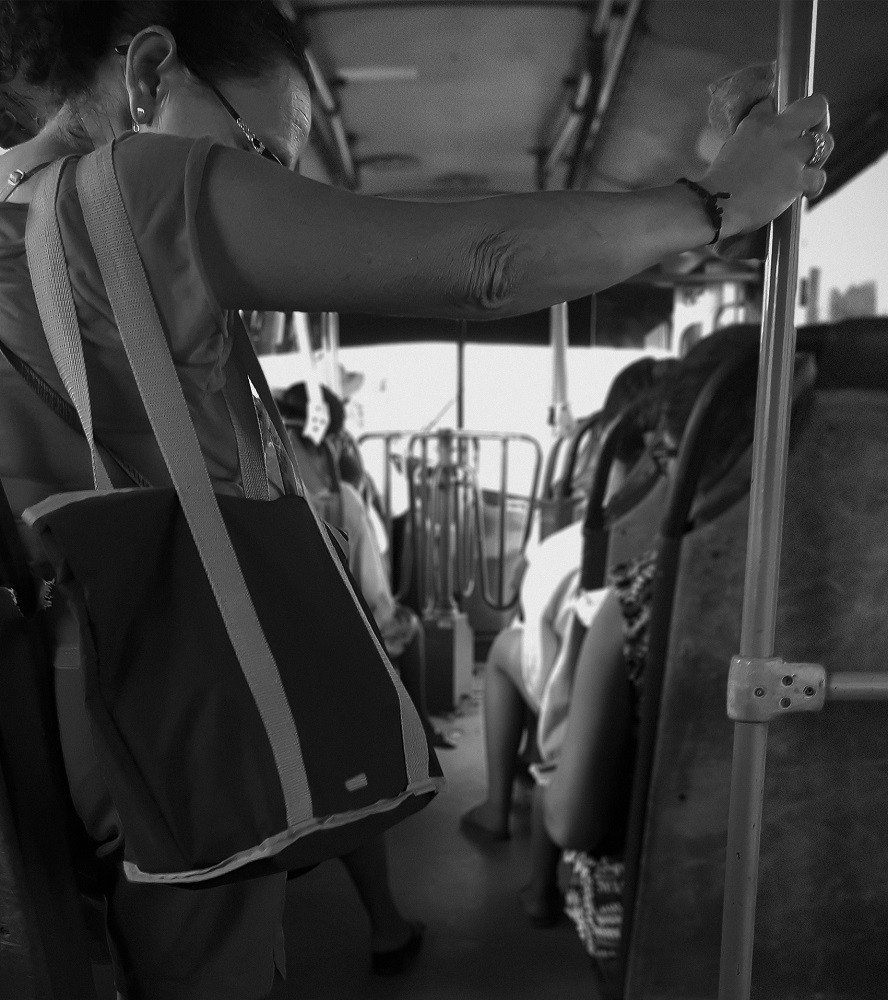 A person is carrying a handbag while riding the bus