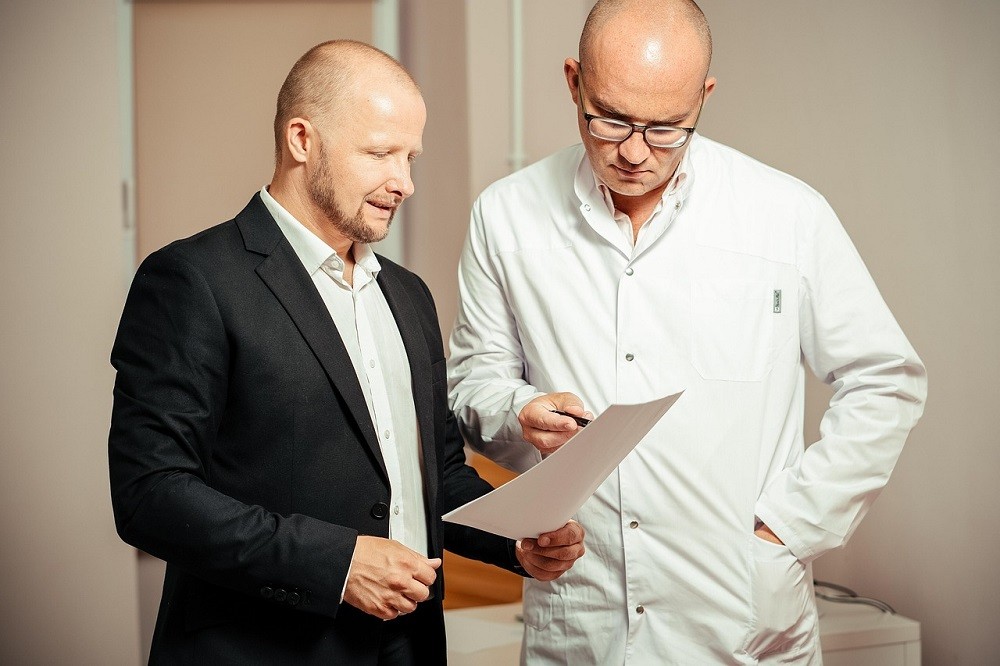 Two businessmen are reviewing a document on printed paper