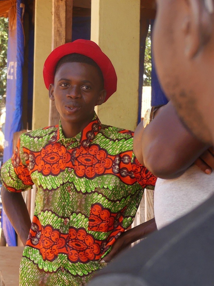 A man dressed in bright colours is talking to someone out of shot. He has a snarky look on his face