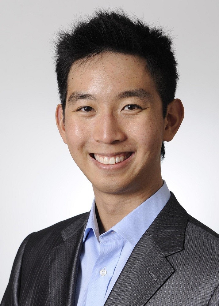 A businessman with black hair is smiling at the camera