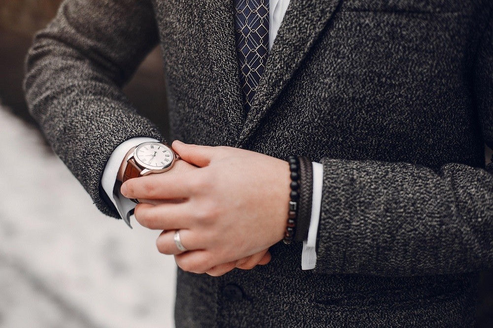 A man in a thick suit jacket is looking at his watch