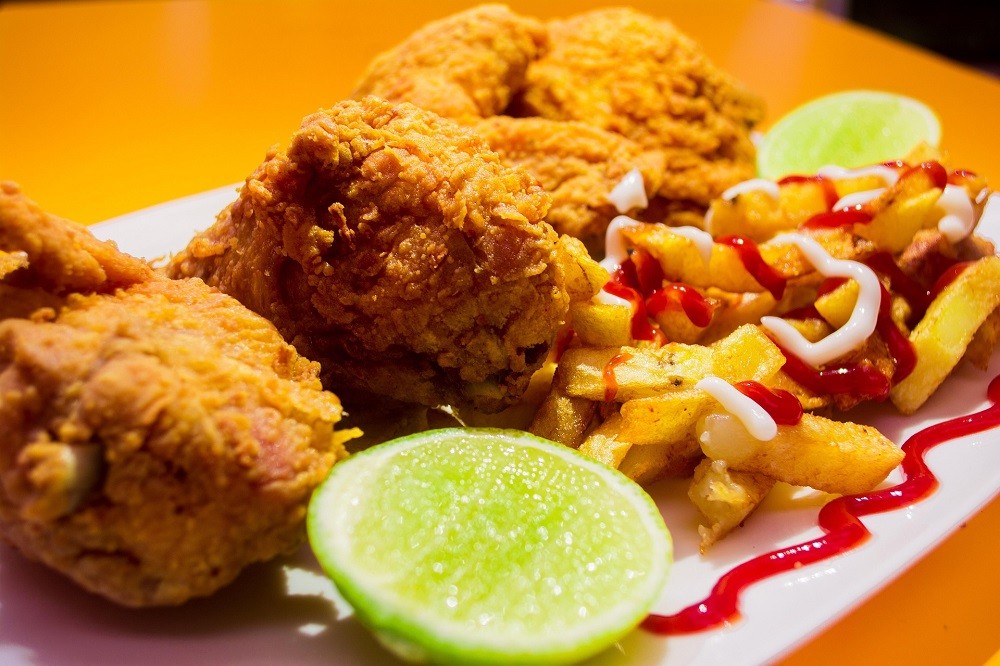 A plate of deep-fried chicken and french fries covered in ketchup