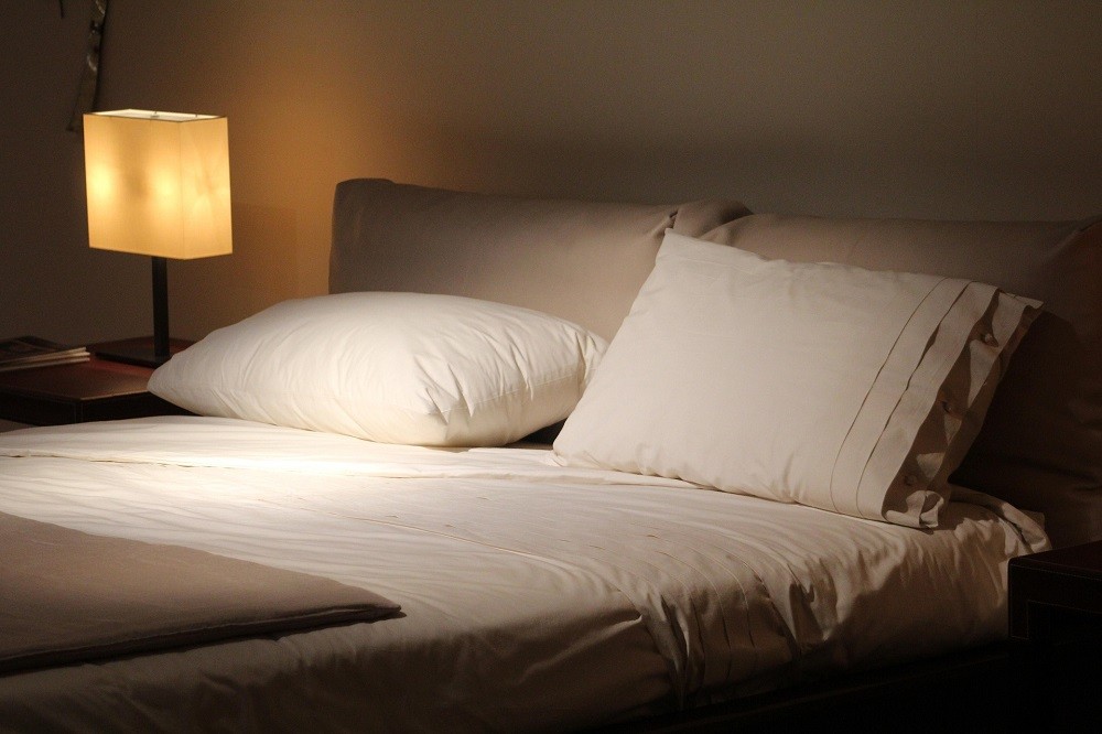 Two big white pillows are propped up on a bed