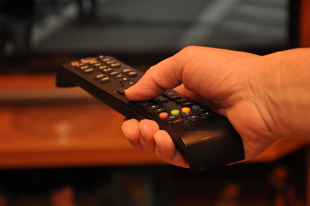 A man holds a TV remove in his hand