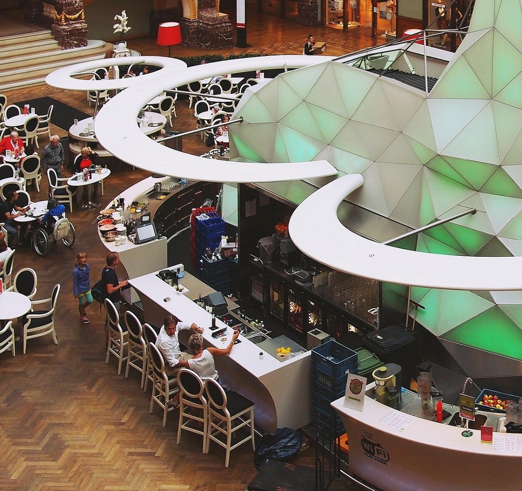 White tables and chairs surround a restaurant in a mall food court