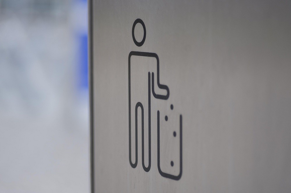 A garbage can pictoid showing a man throwing his garbage in a can