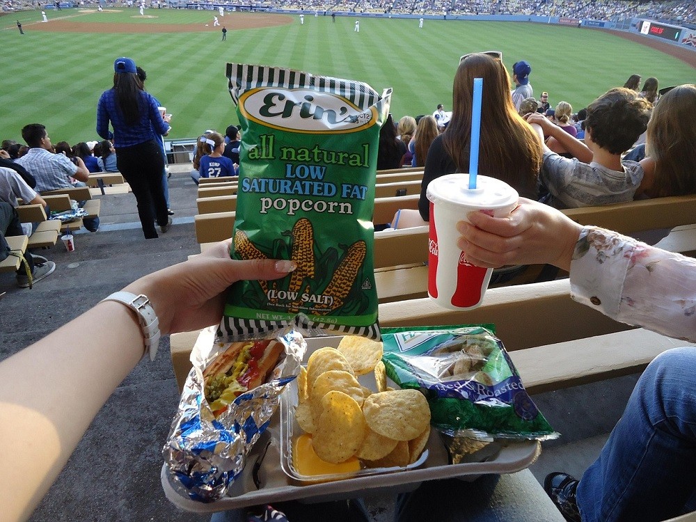 A sports fans with a variety of snacks from a concession stand