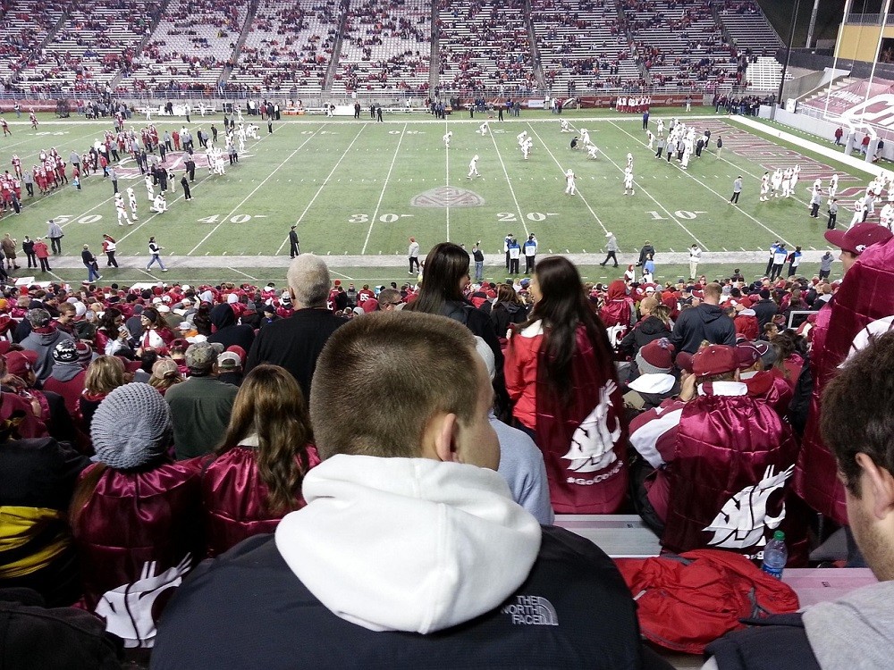 Sports fans wearing team jackets and hoodies at an outdoor football game