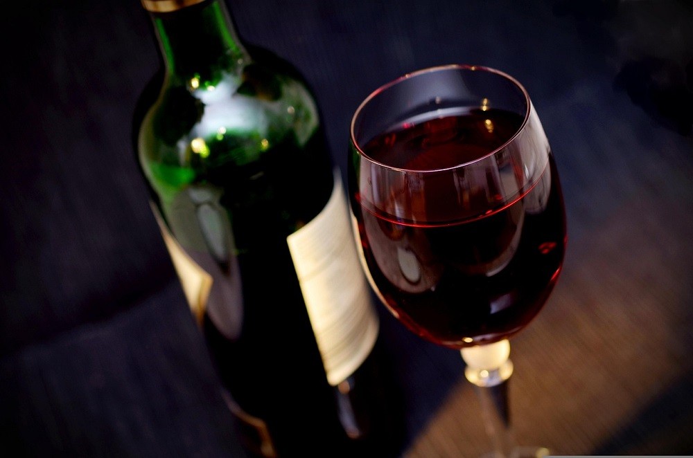 A glass of red wine with wine bottle beside it