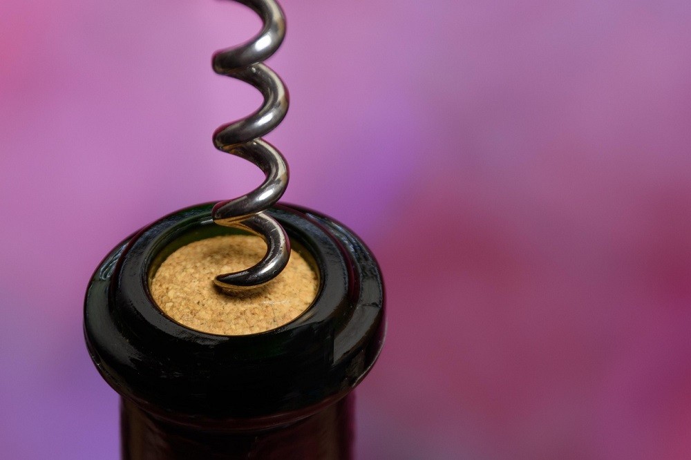 A corkscrew going in to a cork on a bottle of wine