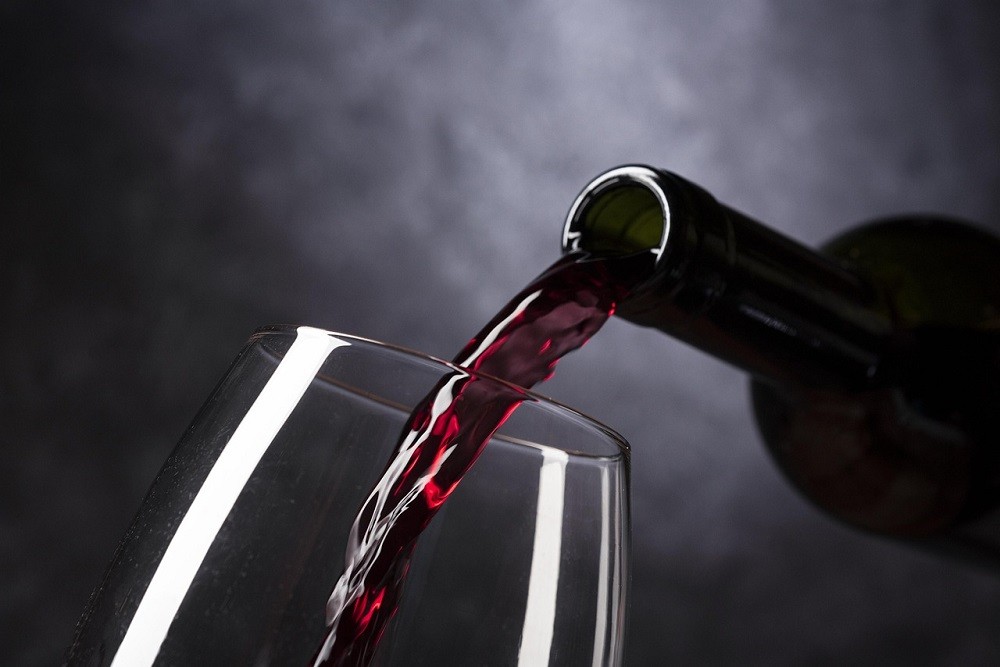 Someone pouring a glass of red wine right from a wine bottle