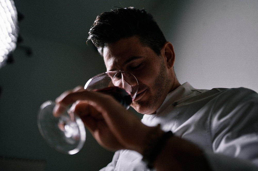A man is nosing his wine, sniffing the aromas from the glass