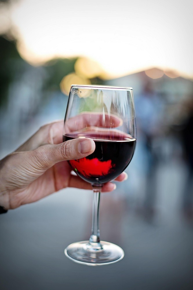 Someone is holding their glass of wine by the bowl which is an incorrect way to hold a glass of wine