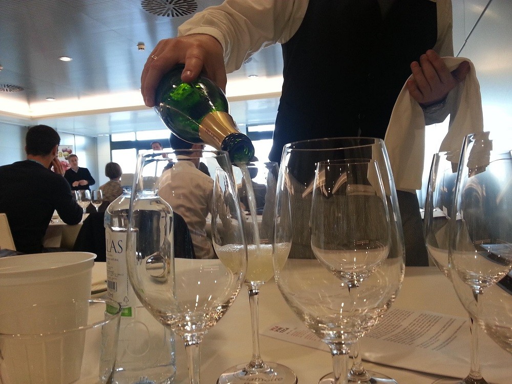 A wine sommelier is pouring white wine into a glass on a table at a restaurant