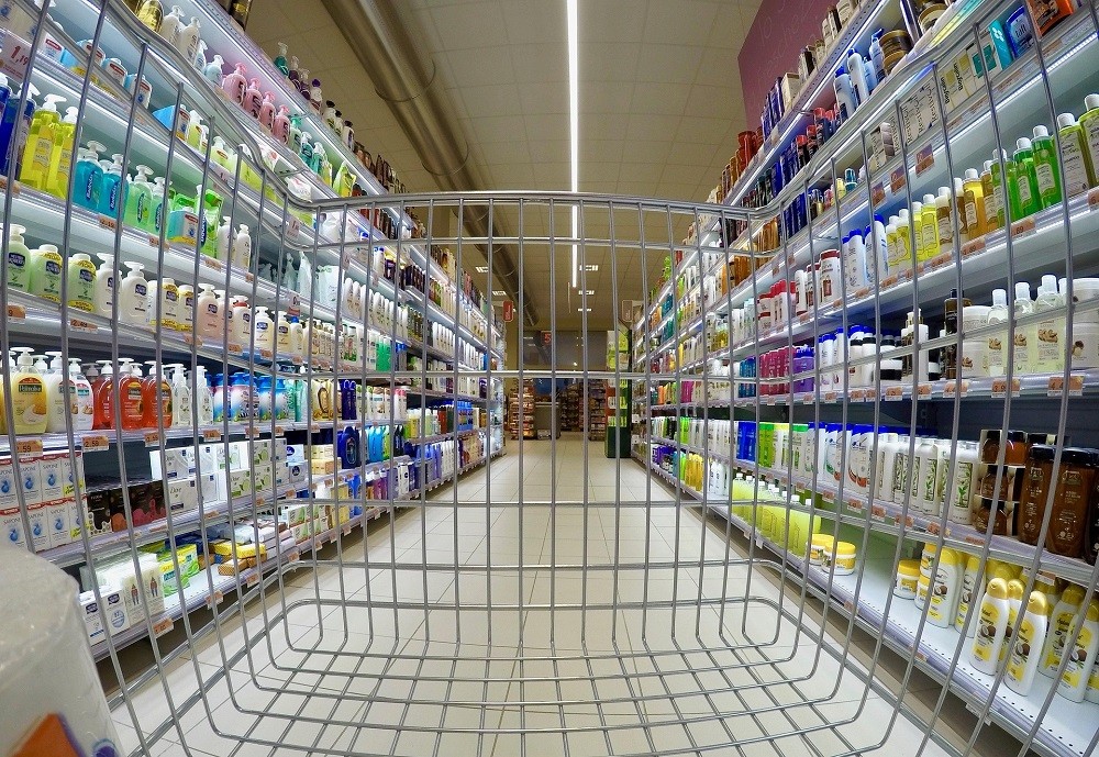 A view from inside a shopping cart going down an aisle of a grocery store