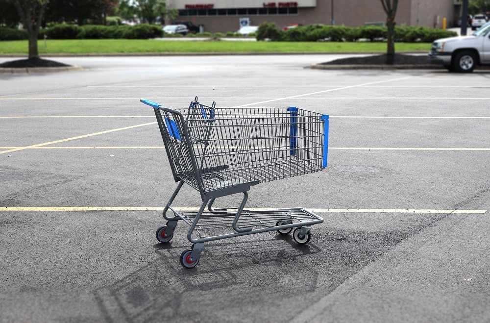 An abandoned shopping cart sits in a parking lot