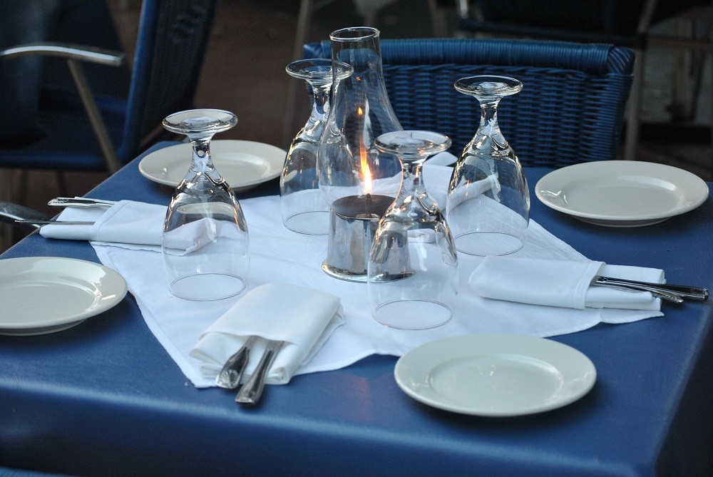 A place-setting for 4 guests including cloth napkins, silverware, white plates, and wine glasses