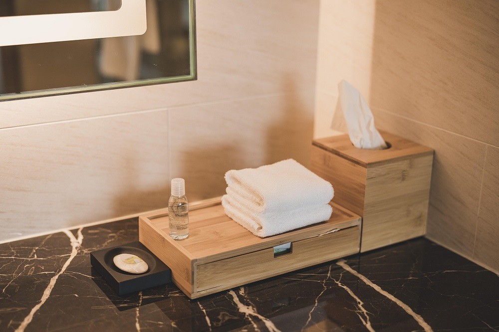 Tissues, hand towels, odour spray, and hand soap are stocked in a guest bathroom