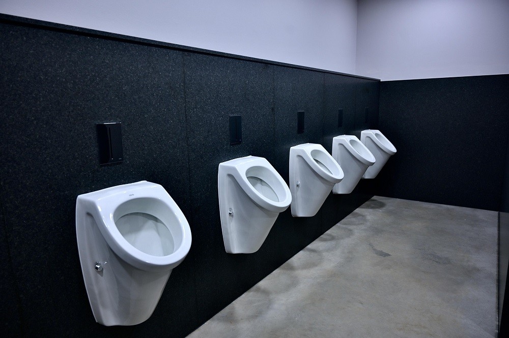 A row of white urinals against a black wall