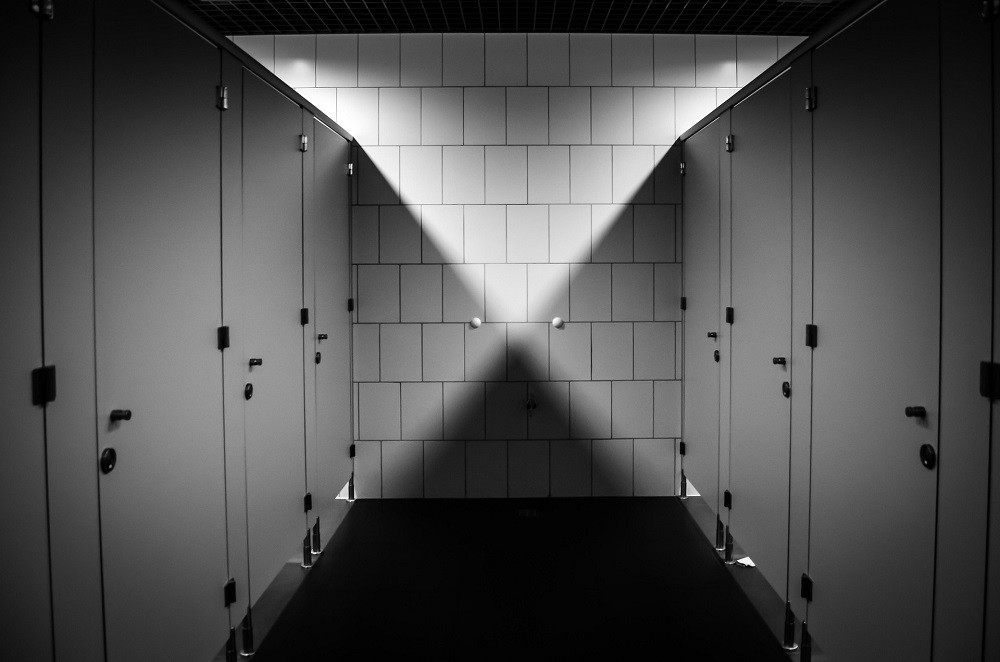 A black and white photograph of public washroom stalls with their doors closed