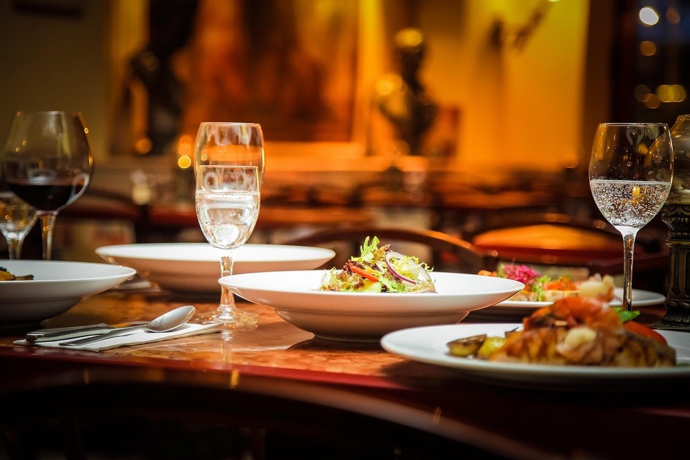A place setting at a restaurant with food, water glasses, and wine glasses already served