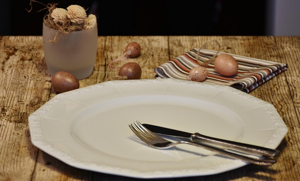 A knife and fork sit in the finished position on the plate with the tips facing 10 o'clock and the handles facing 4 o'clock