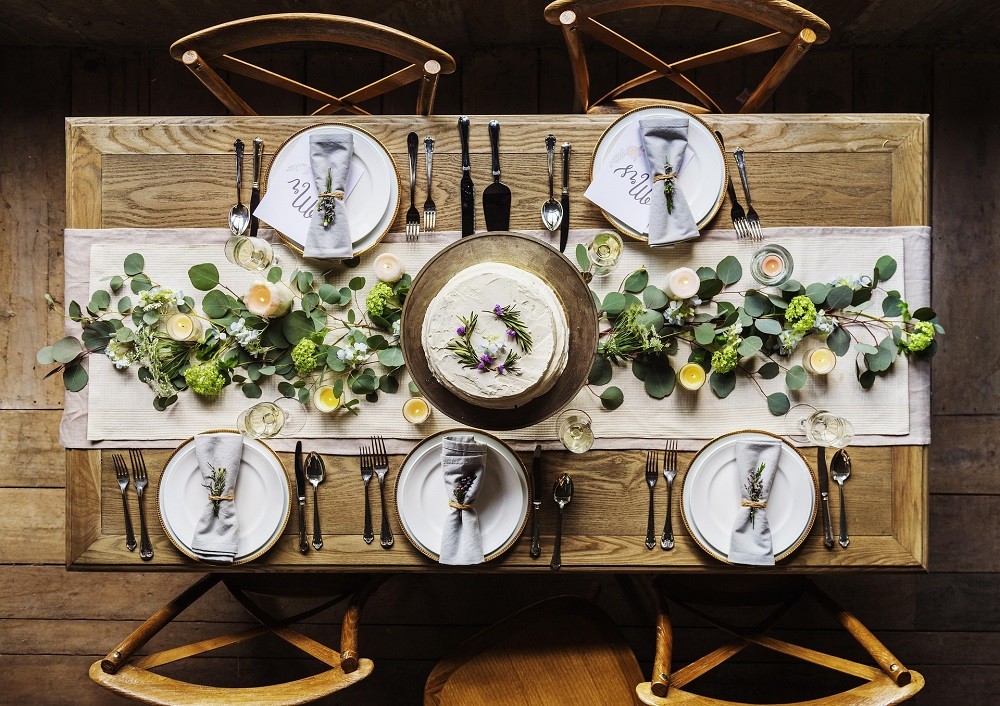 A formal place setting is viewed from above. Every chair has a plate, fork, knife, spoon, napkin, and water glass
