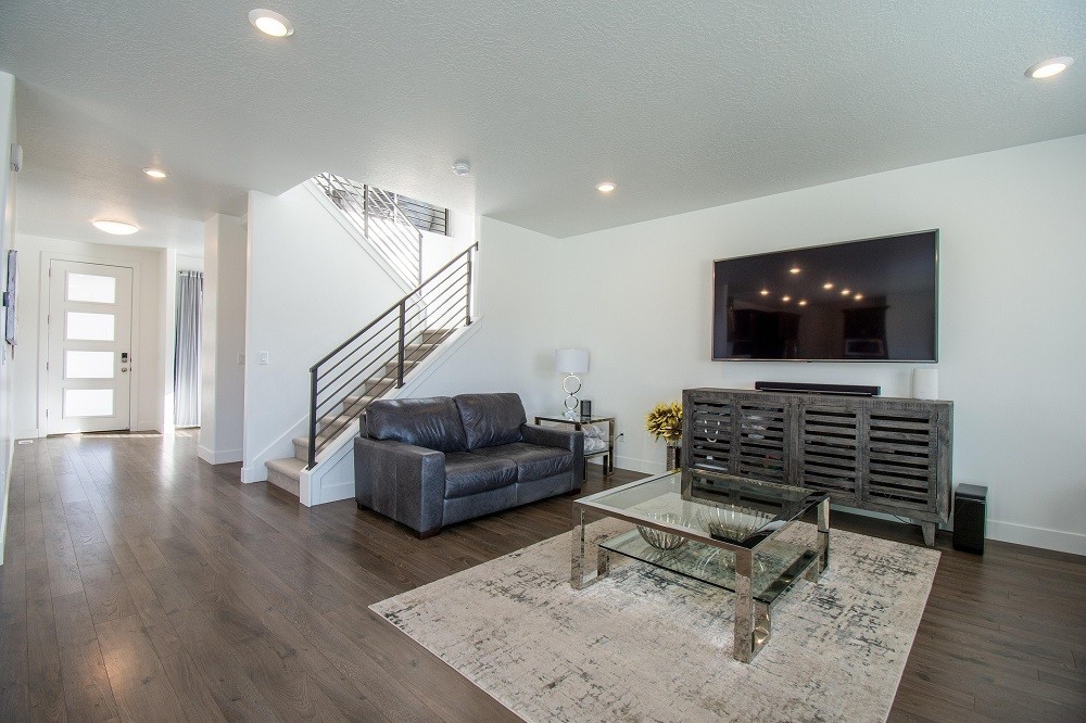A view of someones living room with couch, glass coffee table, entertainment centre, and TV