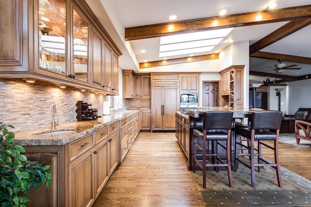 A home showing from the kitchen with light brown cabinets, black chairs, and warm ceiling lights